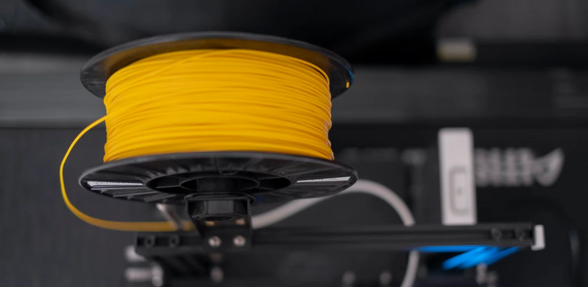A spool of yellow wire sitting on top of a machine by Osman Talha Dikyar on Unspash.